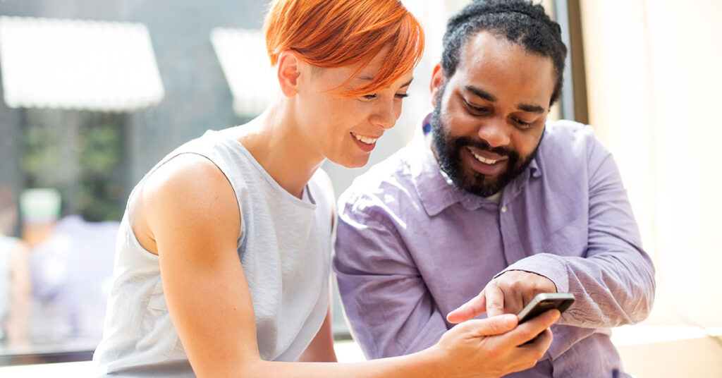 male,female,ginger hair, brown hair, pointing at phone